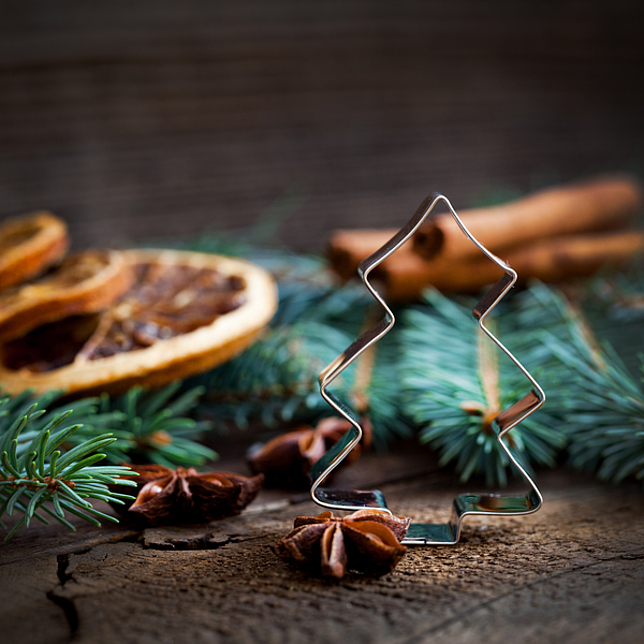 Keksausstecher in Weihnachtsbaumform vor weihnachtlichem Arrangement