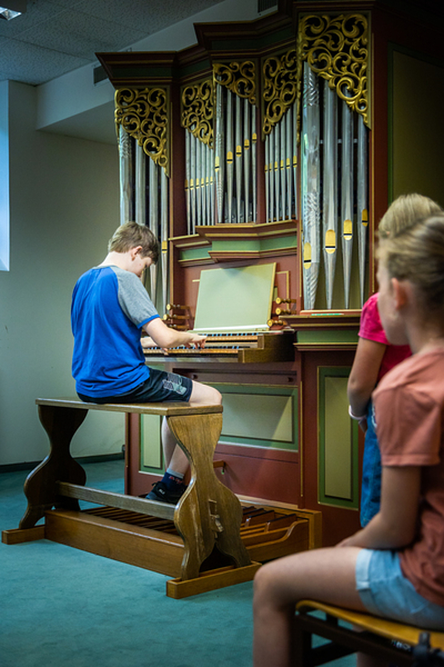 Ein Junge sitzt an einer Orgel und spielt.